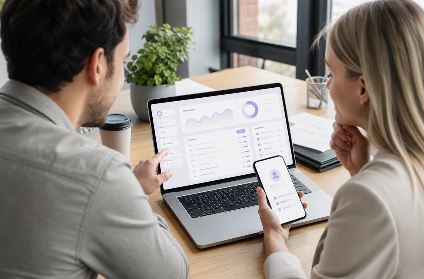 Recruiter and colleague reviewing an Interviewly-style dashboard on laptop and phone
